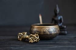 Buddhism Symbols. Antique sound bowl and vajra on a dark backgound.