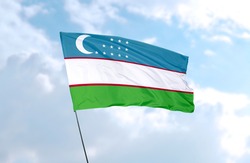 Flag of Uzbekistan in front of blue sky