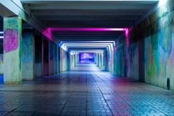 Long luminous tunnel with colorful walls. Underpass with neon lamps