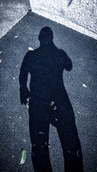 Male shadow on gray asphalt. The shadow of a man on the sidewalk