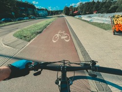 Riding a bike on a bicycle lane. Infrastructure for using bicycles on a daily basis. Bike riding in the city on a sunny day.