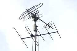 The television aerial or antenna to receive a network in background of white in the sky .
