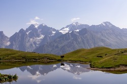 A horse grazing at the Koruldi Lake with a dream like view on the mountain range near Mestia in the Greater Caucasus Mountain Range, Upper Svaneti, Country of Georgia. Wildlife observation.