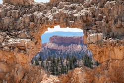 Natural stone arch on Fairyland hiking trail with panoramic aerial view on Boat Mesa and massive hoodoo sandstone rock formations in Bryce Canyon National Park, Utah, USA. Unique natural eroded bridge
