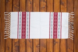 Traditional Romanian napkin or dish towel on empty wooden table. Traditional motif. Top view.