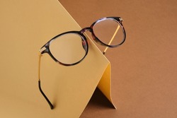 trendy fashion eye glasses on creative paper brown and beige background, vision concept