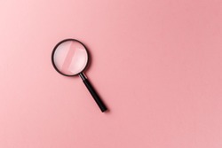 Magnifying glass on pink background. Top view. Flat lay. Copy space. Concept