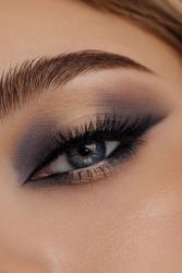 Beautiful macro shot of female eye make-up in smoky eyes style. Blue eye. Creative make-up. Perfect shape make-up and long lashes. Cosmetics. Beautiful eyes make-up. Close-up