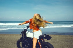 young pretty blonde girl siting on vintage custom motorcycle, outdoor hipster portrait, motorbike, freedom, denim, hair wild, ocean