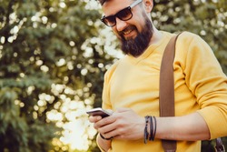 Handsome man beard using smartphone in hand, happy face, street photo, hipster style portrait, backpack, mining bitcoin