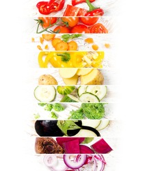 Top view of colorful mix stripes with cut vegetables on white wooden desk; healthy eating concept; rainbow colors; white space for text
