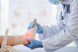 Close-up of pictures of a male orthopedic doctor or orthopedic doctor Wear a medical mask and medical gloves. Going to analyze the cause of ankle bone degeneration In his office at the hospital