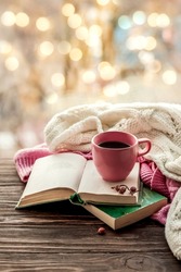 Morning coffee. Cozy composition: a cup of coffee on a wooden table and a warm sweater, an open book. Still life concept. Copy space