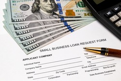 Small business loan form, 100 dollar bills. Concept of financial assistance, stimulus payment and recession during Covid-19 coronavirus pandemic