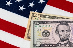 Closeup of ten and five dollar bills with American flag.  Concept of 15 dollar federal minimum wage increase
