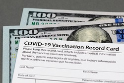 Covid-19 vaccination record card and cash money. Fake, vaccine card fraud and forgery concept