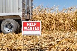 Help wanted sign in farm field. Farm labor shortage, agriculture job market and employment concept