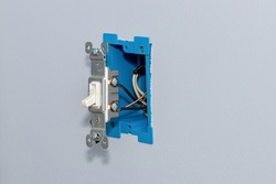 White electrical light switch and wiring in wall. DIY home maintenance, remodeling and electricity repair concept