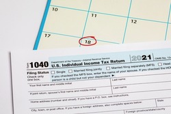 Income tax return form and calendar with filing deadline date. April 18 tax due date, financial information