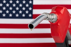 Gas dripping from fuel nozzle with American flag. Gasoline shortage, price and ethanol concept.