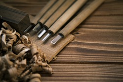 Close-up view of a set of wood chisels for carving wood, sculpture tools on the wooden background surrounded by wooden chips. High-quality photo