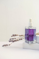 Lavender oil in a bottle on white background next to dry lavender flowers, vertical orientation
