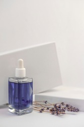 Lavender oil in bottle on white background next to dry lavender flowers, vertical orientation. Violet oil