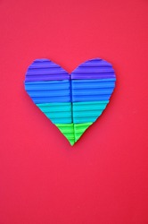 Multi coloured valentines heart made from pieces of plasticine modelling clay against a background of coloured paper. Symbol of romantic love in bright candy colours. Pop art style image