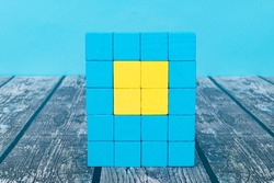 Blue wooden blocks are stacked vertically in a square and yellow blocks are arranged in the center
