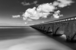 Black and white photo of the seven mile bridge stretching in to the horizon in the Florida keys. 