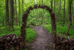 A metal arched gateway at Char-Mar Ridge Park in Westerville leading to a hiking path in the forest. 
