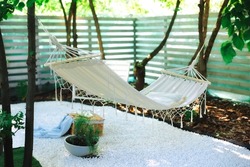  Comfortable Hammock hanging hanging on tree in summer garden. Cozy hygge place for weekend relax in yard.  Cozy exterior backyard. Hammock in boho style hanging on tree. Concept of recreation outdoor