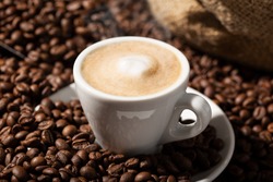 Cappuccino or Coffee with milk cup and roasted beans. Coffee background
