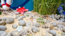 Seascape with fishing net, sea pebbles, sea sand and red starfish close-up. The concept of summer holidays, fishing and travel.