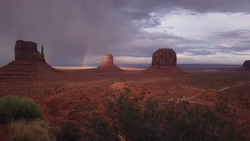 The Monument Valley Navajo Tribal Park in Arizona, USA. View of a storm and double rainbow over the West Mitten Butte, East Mitten Butte, and Merrick Butte Monuments.