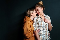 Portrait of young gay couple, lesbian women hugging on black background with copy space. Сoncept of love, family, gay marriage and pride