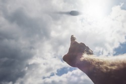 Hand points to the UFO in the sky. The day of the UFO concept of a conspiracy