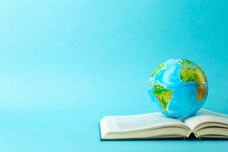 Earth globe on an open book on a blue banner background. Knowledge, learning, study concept. Backagrund education