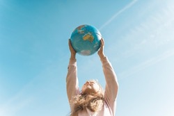 Child with Earth Globe. Portrait of a blonde European girl of elementary school with an educational globe of the planet Earth in nature in sunny weather. Study, education, conservation and