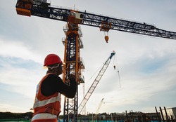  Rigger signal crane at construction site with walkie;talkie 