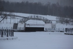 Humpback bridge over the park's snow-covered white lake