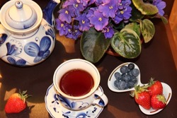 Beautiful serving for a tea party. A cup of fragrant tea,  blue violet and fresh berries