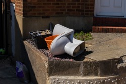 Discarded white porcelain toilet in a suburban front garden after home renovations