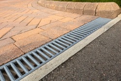 Galvanised steel drainage channel in a red block paved residential driveway