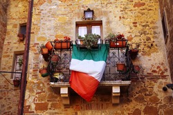 Typical Italian balcony with flag and flowers in Montepulciano (Tuscany)