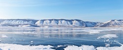 Baikal Lake in winter. Panorama of the frozen Small Sea Strait on a sunny frosty February day. View of the Sarma gorge and snow-capped mountains. Focus in the center of the panorama