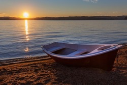 Baikal Lake on sunny early summer morning. Fishing boat on the sandy shore of the Small Sea at dawn. Beautiful seascape. Holidays on the coast, fishing and travel