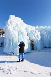 Baikal Lake on sunny winter day. Favorite pastime of tourists is photographing unusual icy rocks of Olkhon Island, covered with bizarre icicles. Unforgettable ice travel, winter outdoor recreation