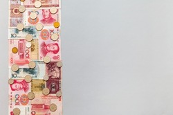 Row of paper banknotes of different denominations of Chinese Yuan money and coins on light table. Free empty space for text on right. Financial background. Concept of mutual settlements 
