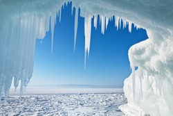View of the frozen Lake Baikal through the ice arch with icicles